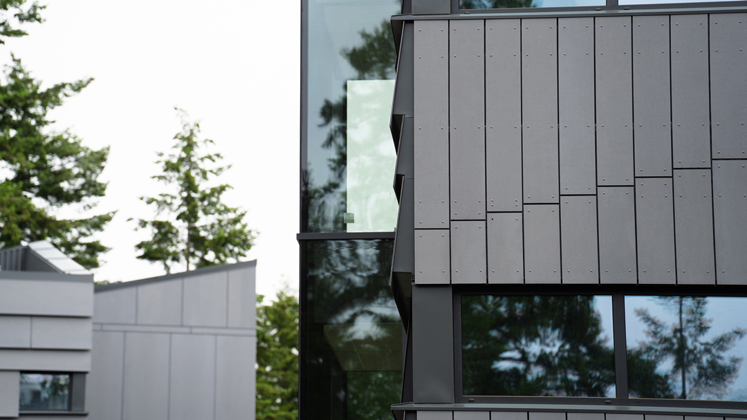 Exterior photo of CV student housing, tul'al'txw, surrounded by tall fir trees.